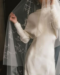 a woman in a white dress and veil with writing all over her face on the wall