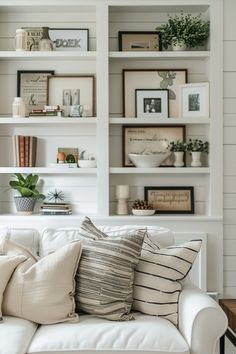 a white couch with pillows and pictures on the wall