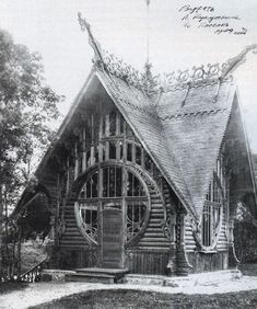 an old photo of a log cabin with a large window and circular wooden wheel on the roof