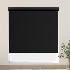 a black roller blind in front of a white wall with a plant on the window sill