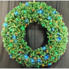 a green wreath with multicolored lights on it