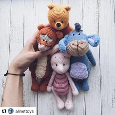 a hand is holding several stuffed animals on a white wooden surface with planks in the background