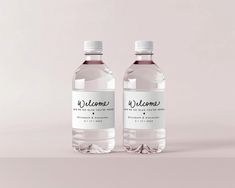 two bottles of water sitting next to each other on a pink surface with the words welcome