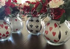 four vases with hearts and playing cards on them sitting on a table next to flowers