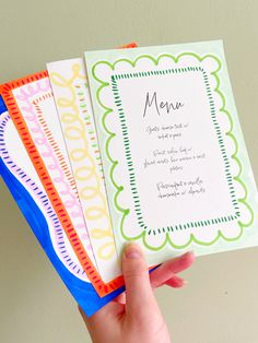 a person holding four different colored menu cards