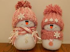 two snowmen wearing hats and scarves on top of a wooden table