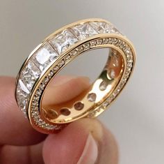 someone is holding up a gold wedding ring with white stones on the inside of it