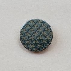 a button with an abstract design on it sitting on a wall next to a white wall