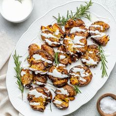 a white plate topped with potatoes covered in sour cream and sprinkled with rosemary