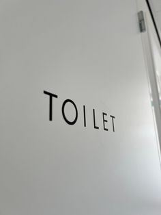 the word toilet written in black on a white wall