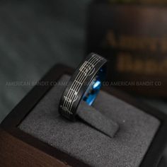 a black and blue ring sitting on top of a wooden box next to a book