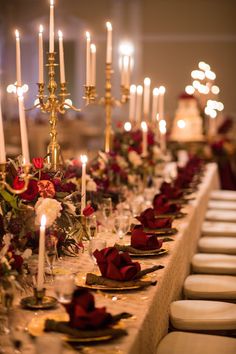 the long table is set with many candles and place settings for guests to sit at