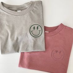 These comfy Bella Canvas colored tees are embroidered with a cute little smiley face. Choose from classic, heart/bolt eyes, or lightning bolt eyes. Please leave the thread color in the personalization box. Please wash on cold and dry on a normal cycle. Cute Long Sleeve T-shirt With Embroidered Text, Cute Embroidered Relaxed Fit Tops, Cute Embroidered Tops With Relaxed Fit, Cute Crew Neck Top With Embroidered Text, Cute Tops With Funny Print For Everyday, Trendy Smiley Face Tops For Everyday, Relaxed Fit Smiley Face Top For Everyday, Everyday Relaxed Fit Top With Smiley Face, Everyday Relaxed Fit Smiley Face Top