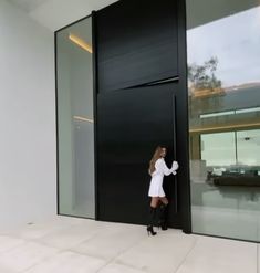 a woman standing in front of a black door