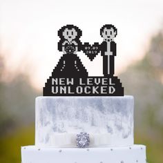 a wedding cake topper that says new level unlocked with a bride and groom holding hands