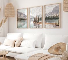 three paintings hang on the wall above a couch in a living room with white furniture