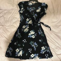 Girls Hollister Floral Wrap Dress Size Xs. Nwot! Never Worn. Tie At The Side Of The Waist. Cute Black Mini Dress For The Beach, Cute Black Mini Dress For Beach, Cute Black Dress For Vacation, Cute Black Floral Print Dress, Cute Black Dress With Floral Print, Cute Black Dresses With Floral Print, Floral Wrap Dress, Hollister Dresses, Wrap Dress Floral