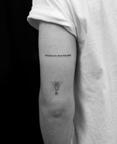 a black and white photo of a person's arm with a bee tattoo on it