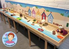 there is a long table with many toys on it and a cartoon beach scene painted on the wall