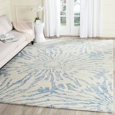 a white and blue rug in a living room next to a couch with a window