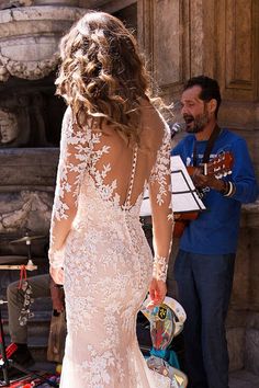 a woman in a wedding dress standing next to a man with a guitar and violin