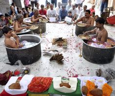 many people are gathered around large metal tubs filled with food