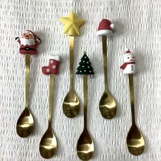 six spoons decorated with christmas decorations and santa clause on the top one is gold