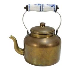 a brass tea kettle with a white handle