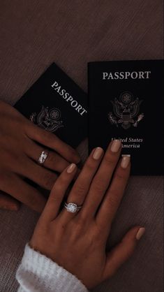 two people holding their hands next to a passport and ring on top of each other