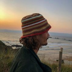 a man wearing a knitted hat looking out at the ocean