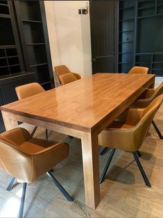 a wooden table with six chairs around it in a room filled with bookshelves