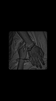 black and white photograph of two hands on top of each other with chains attached to them