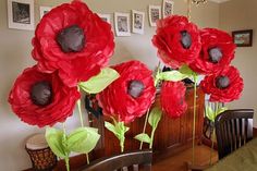 some red flowers are sitting on a table in front of a mirror and other pictures