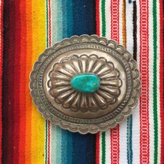 "This piece is a beautiful oval belt buckle with scalloped edges and 1 large cabochon natural turquoise handset in the center. Great gift for an anniversary, birthday or an amazing wedding suit addition for a southwestern vibe. 56 grams for the entire piece 3\" long 3.4\" wide 1\" thick including buckle Signed by artist Ray Adakai. If you have questions about this item etc please ask before you purchase. Sold as-is, no returns or exchanges on any jewelry. Free domestic shipping Thanks for lookin Oval Concho Jewelry Gift, Western Oval Engraved Jewelry, Western Style Oval Engraved Jewelry, Western Style Oval Concho Jewelry, Artisan Oval Concho Jewelry, Southwestern Turquoise Jewelry With Antique Buckle, Pioneer House, Turquoise Belt Buckle, Turquoise Belt