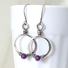 Eco friendly sterling silver (16G) has been hand formed and hammered into hoops. An organic spiral has been wire wrapped around a 4mm purple fossil stone bead. The hoops have been oxidized and lightly brushed with steel wool and then polished for a soft patina. Perfect earrings for the holidays! Ear wires are hand formed from sterling silver. Earrings measure 1.75 inches from top of ear wire to bottom of teardrop. The widthr at widest part is 7/8 of an inch. All silver used has come from a recyc Nickel Free Small Hoop Earrings For Gift, Everyday Sterling Silver Pierced Jewelry, Sterling Silver Hoop Jewelry Gift, Sterling Silver Hoop Jewelry For Gifts, Sterling Silver Hoop Jewelry As Gift, Minimalist Cadmium-free Dangle Earrings, Adjustable Nickel-free Sterling Silver Hoop Earrings, Adjustable Small Hoop Sterling Silver Jewelry, Small Hoop Sterling Silver Pierced Earrings