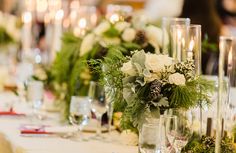 the table is set with candles, flowers and greenery for a festive dinner