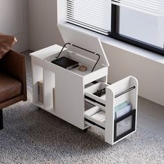 a small white desk with drawers and a chair in front of a window on carpeted floor