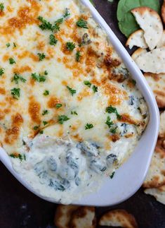 a casserole dish filled with cheese and spinach garnished with parsley