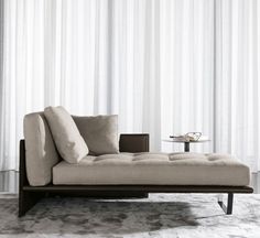 a living room with a couch, coffee table and white curtained window coverings