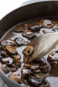 a wooden spoon in a pot filled with mushrooms