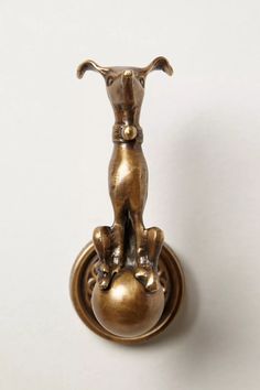 a brass door knock with a dog sitting on it's back and holding onto the handle