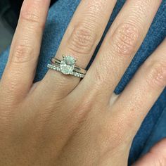 a close up of a person's hand with a diamond ring on their finger