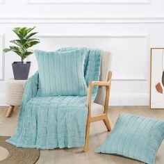 a chair with a blanket on it next to a potted plant and a rug