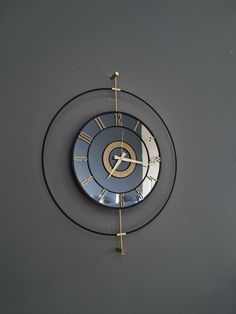 a clock that is on the side of a wall with a gold and black design