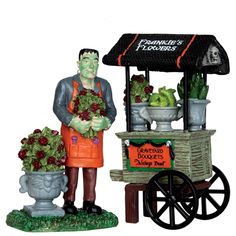 a statue of a man selling flowers in front of a food cart with fruit and vegetables