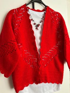 a red cardigan sweater hanging on a white wall