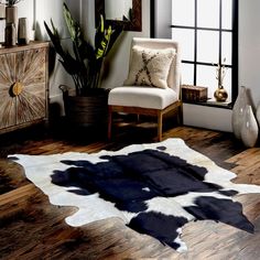 a living room with a cow hide rug on the floor next to a chair and window