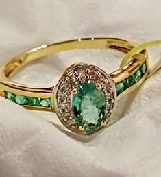 This ring features: * 1 x oval cut Zambian emerald gem measuring approx 6x4mm with a minimum gemstone weight of 0.39ct. * 8 x round cut Zambian emerald gems measuring approx 2mm with a minimum gemstone weight of 0.23ct. * 16 x round cut diamonds measuring approx 1mm with a minimum gemstone weight of 0.08ct. * The total weight for this piece is 0.73ct. * The ring sits approx 5mm above the finger and measures approx 9mm down the finger. * The band measures approx 3mm at the shoulder and tapers to Green Oval Cluster Ring Fine Jewelry, Oval Green Gemstone Cluster Ring, Green Oval Diamond Ring Fine Jewelry, Formal Green Oval Cluster Ring, Formal Oval Green Cluster Ring, Oval Emerald Ring With Halo Design, Green Oval Diamond Ring With Center Stone, Oval Emerald Ring With Halo Setting, Oval Emerald Birthstone Ring With Halo Setting