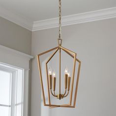 a chandelier hanging from the ceiling in a room with white walls and windows