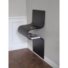 a black chair sitting on top of a wooden floor next to a wall mounted shelf